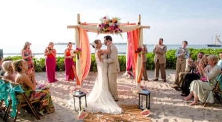 couple during wedding ceremony at pier house resort & spa on beach under ceremony arch